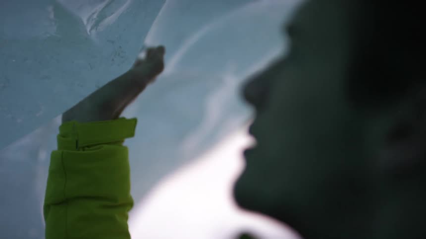 A man in an ice cave runs his fingers over the ice