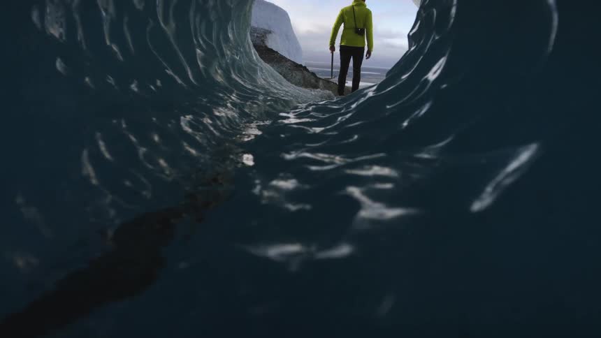 A person walking out of a glacier tunnel