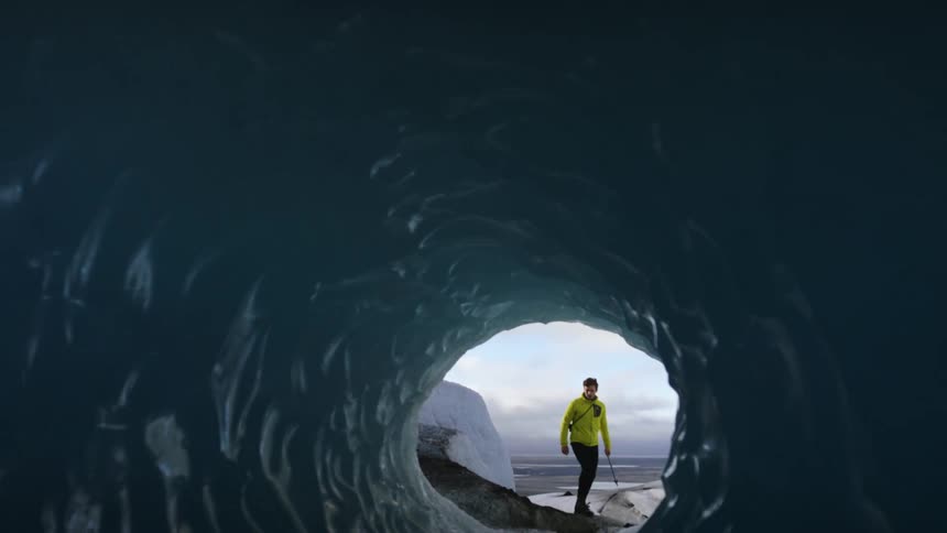 A man carrying an ice pick walks in to an ice tunnel