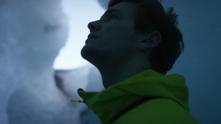 A man is searching around the ice in the cave