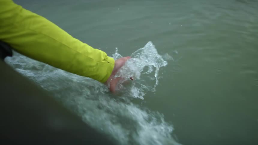 A person putting their hand in water off a boat