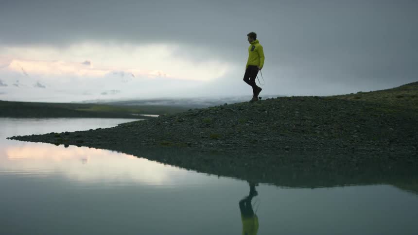 A man hiking down a hill to a lake