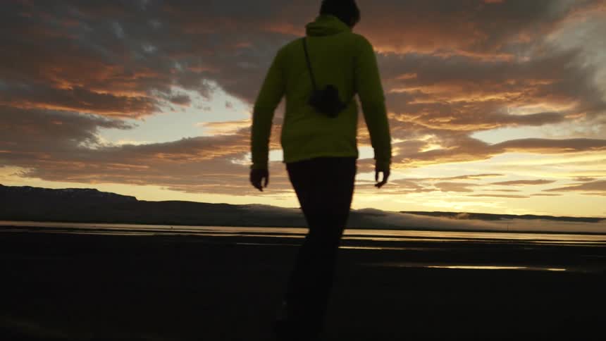 A man is walking by the beach at dusk