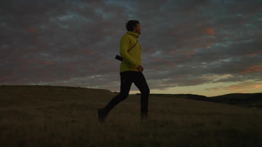 A man is hiking outdoors at dusk