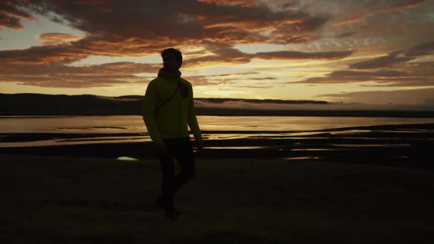 A man is standing outdoors while the sun is setting