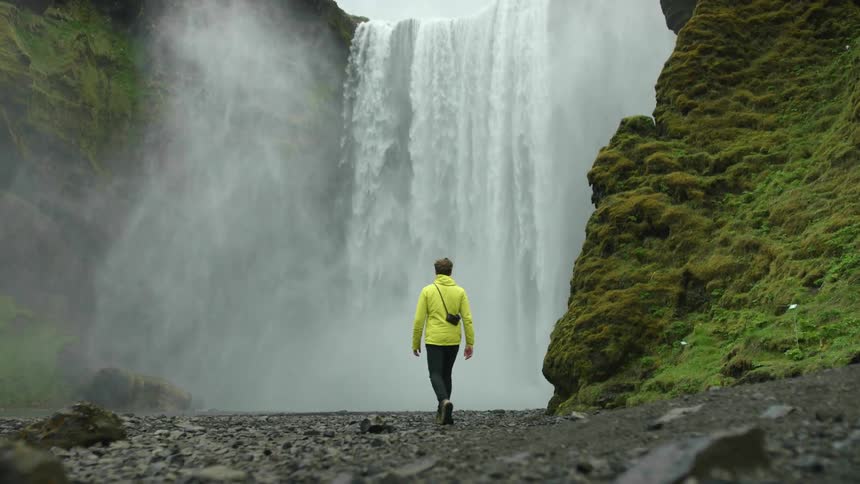 A man walking towards a waterfall