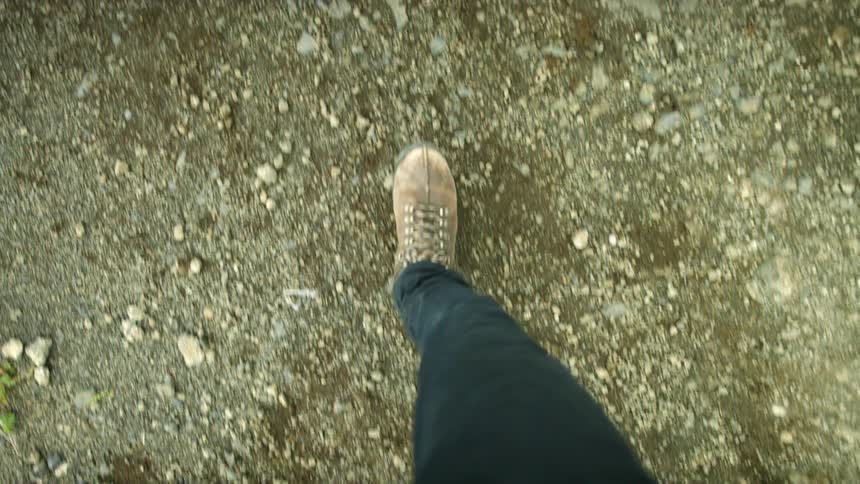 A hiker walking over dirt and rocks in nature