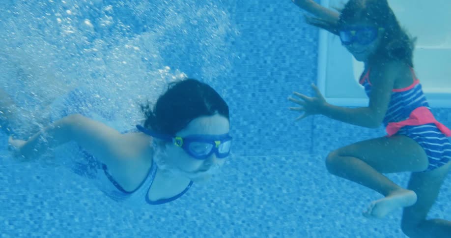 A young girl dives into a pool with other children