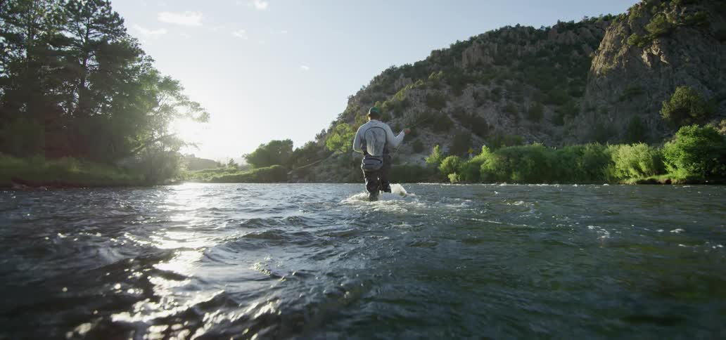A man fishing while standing in a river