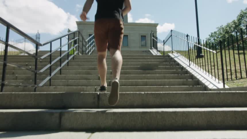 A man jogs up a stone staircase leading to a tall tower