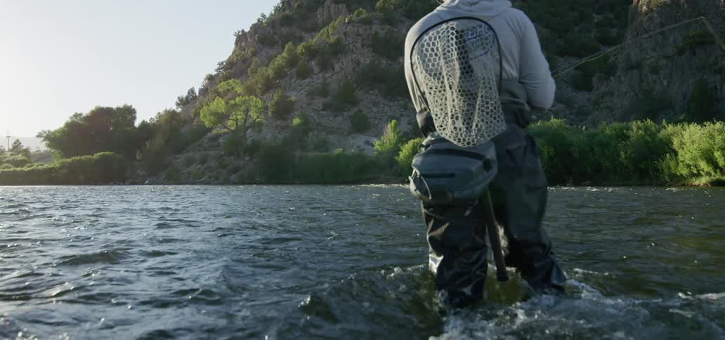 A man stands in the water and fishes
