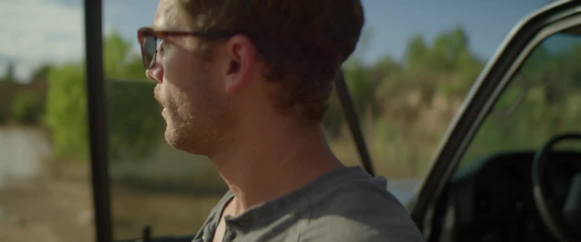 A man gets out of his car by the lake