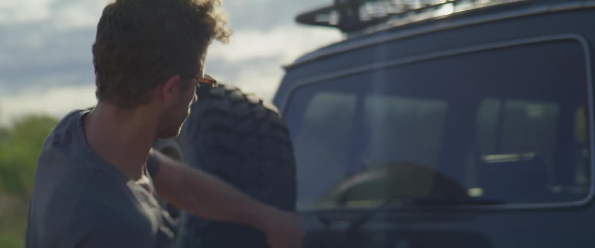 A woman gets out of a vehicle and walks to the back where a man opens it up so they can get their backpacks