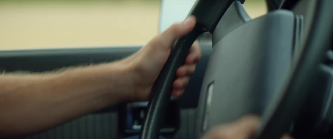 Male driver turns to control the direction that the vehicle goes in