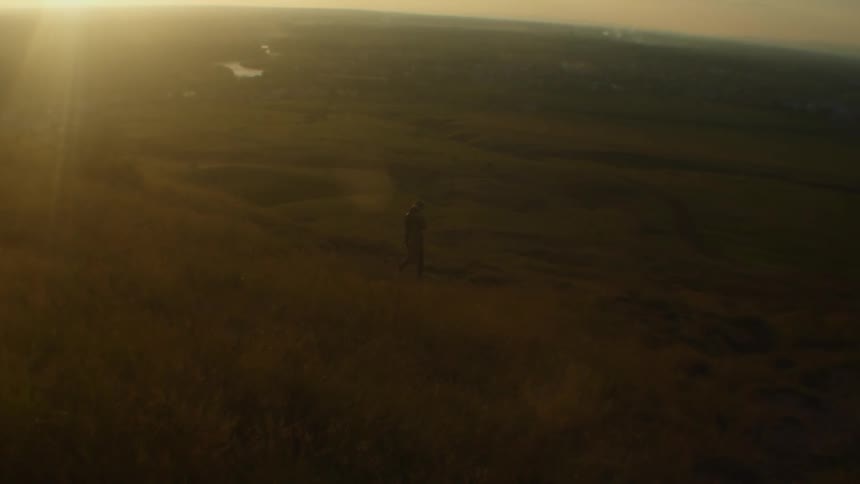 A person is walking through a rural area at dusk