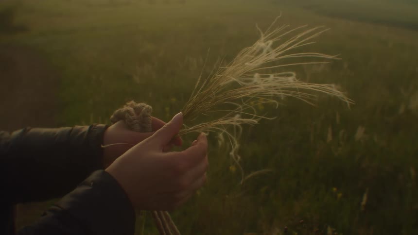 A man smooths out a bouquet of weeds he picked from a field