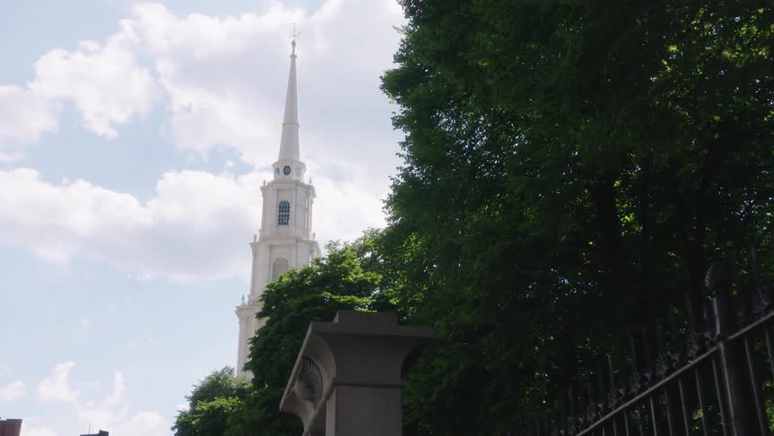 A view of a church steeple from a sidewalk