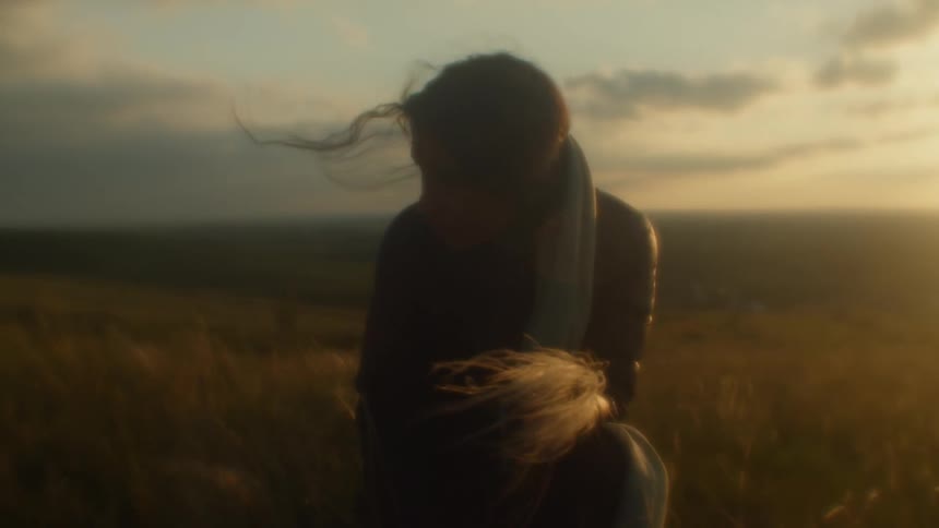 A woman kneeling in a field holding a handful of wheat