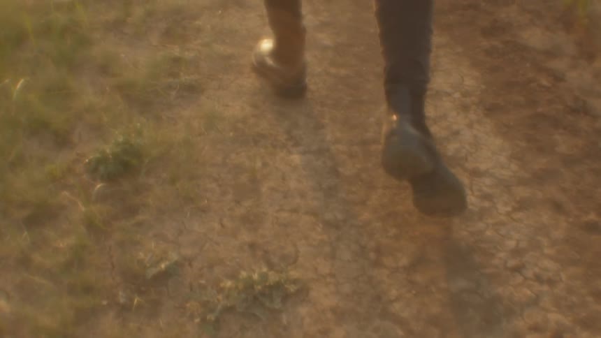 A person is walking outdoors in the dirt