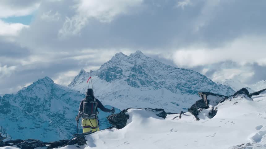 A man standing at the top of a mountain covered in snow