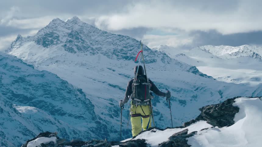 A skier stands and looks down a mountain