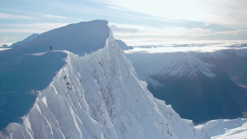 An aerial view of a person standing on a snow covered mountain