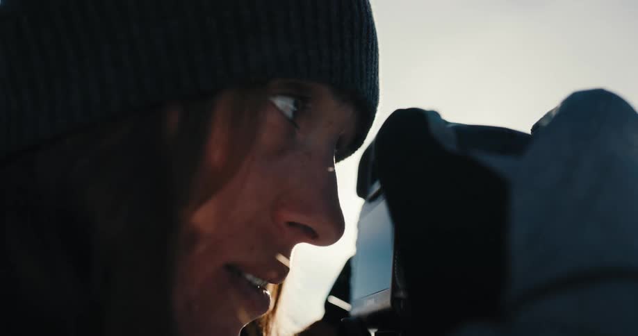 Side view of a woman with a beanie taking photographs with a camera