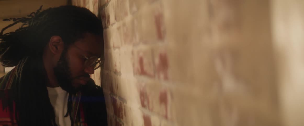 A man is standing with his head against a brick wall