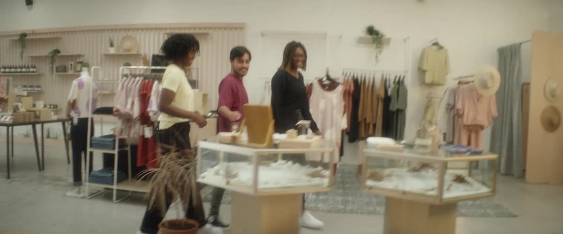 A group of three friends stop at a jewelry display case as they walk through a store