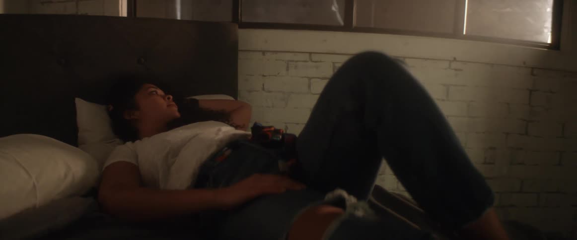 A teenage girl lying on a bed in a dark room