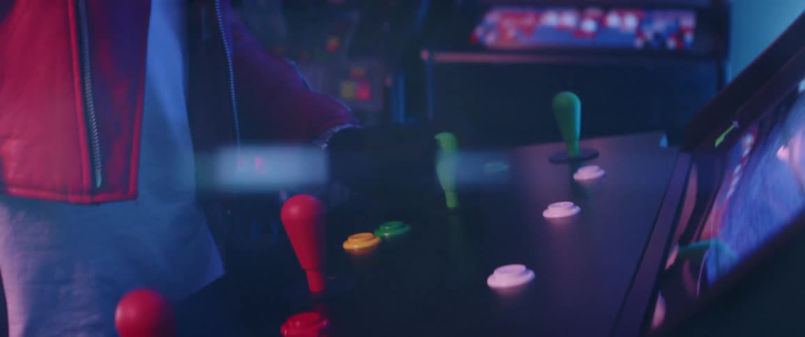 A person with a red jacket standing and pushing a button in an arcade
