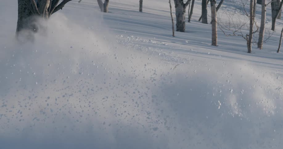 A skier kicks up snow as he leaves a trail going down a mountain