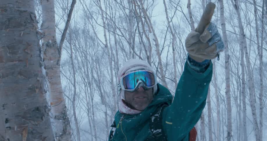 A man is pointing his finger outdoors while standing in a forest