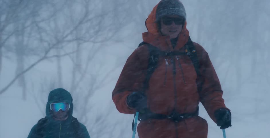Two men walking in a snow storm on a mountain