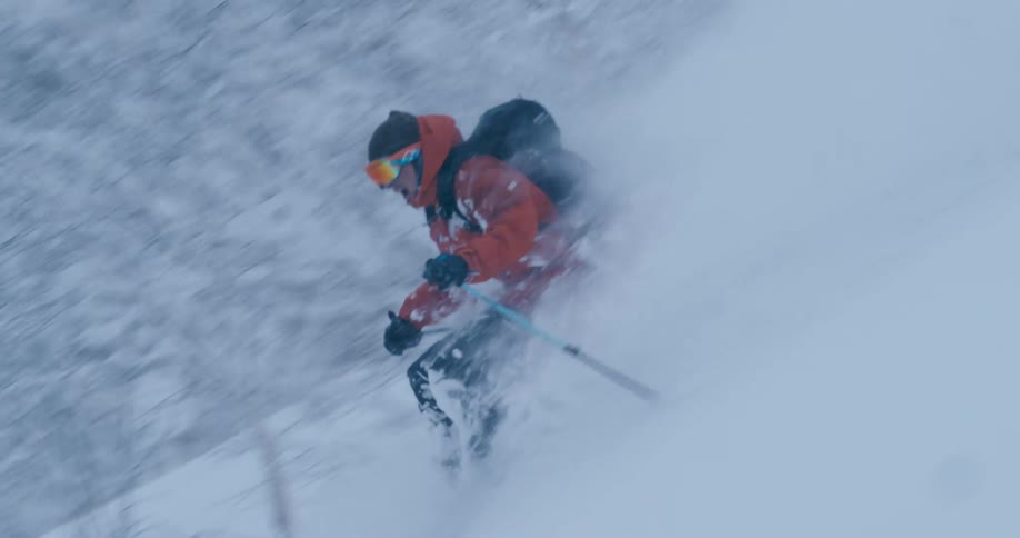 A skier descends a mountain slope as heavy snow falls from the sky