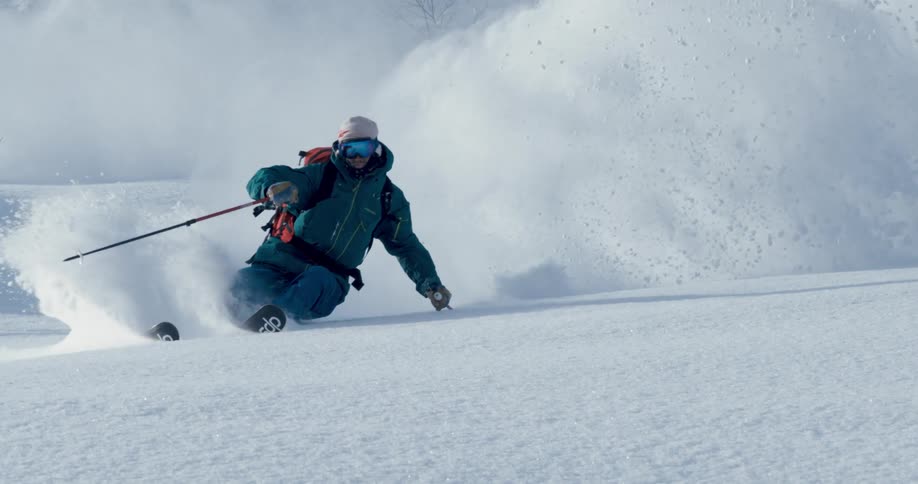 A man is skiing down a mountain in deep snow