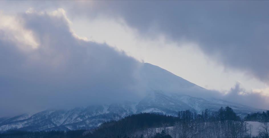 Clouds moving over a snow covered mountain range