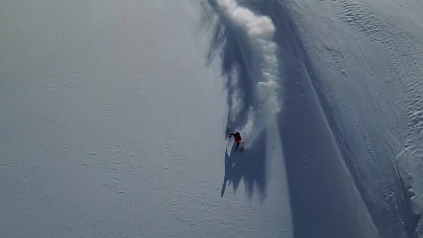Skier skis down snow covered mountain slope past shadowy dips