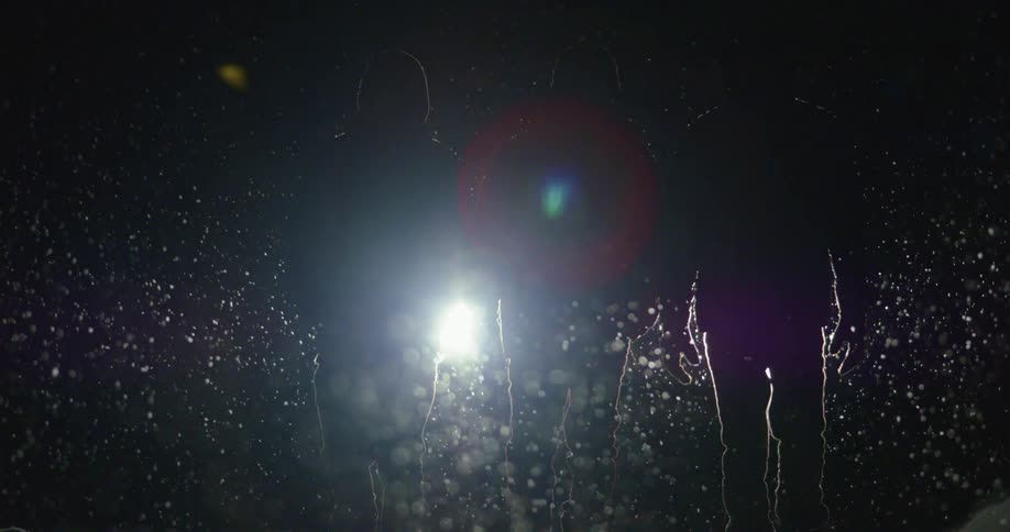 Silhouette of three people walking at night under a light snowfall