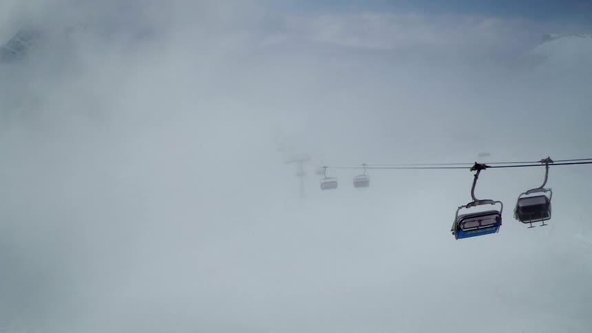 A cable lift with a mountain range the sky and clouds in the background