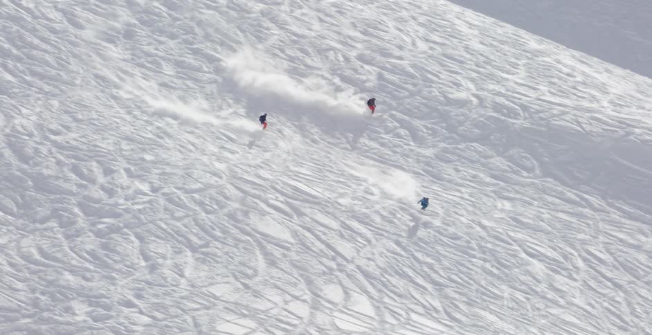 Three people racing as they ski down a hill