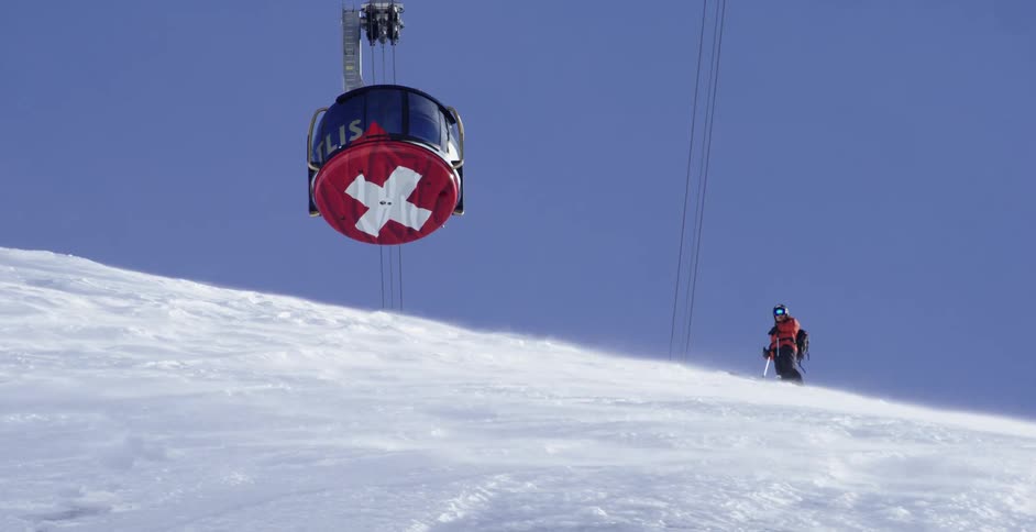 A gondola rides over a snow covered mountain under a clear blue sky