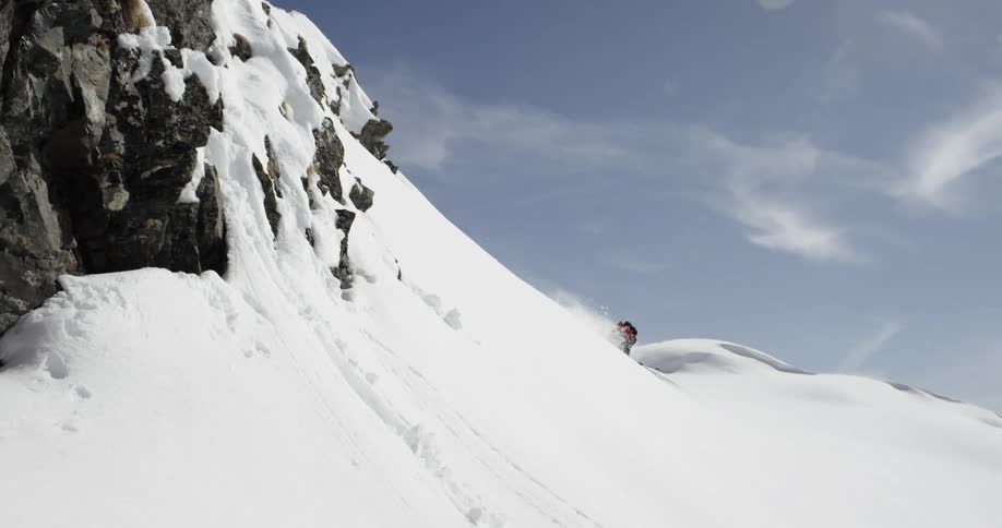 A skier jumps off a ledge while skiing down a mountain