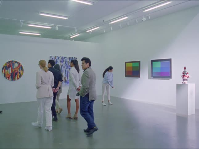 People standing and walking in a museum with paintings