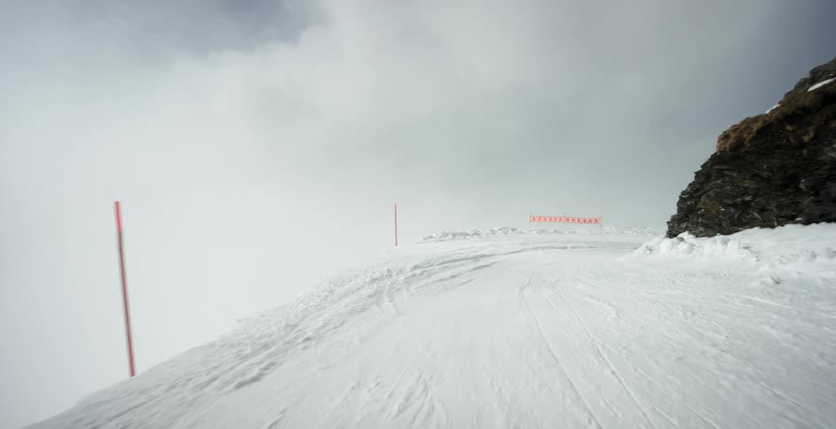 Snow covered path curves around stone outcropping passing posts holding sign banner