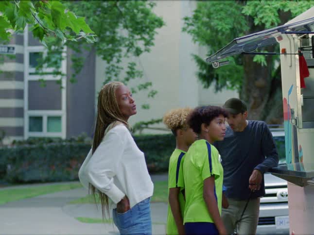 A family talks among themselves as they approach a food truck and examine its menu