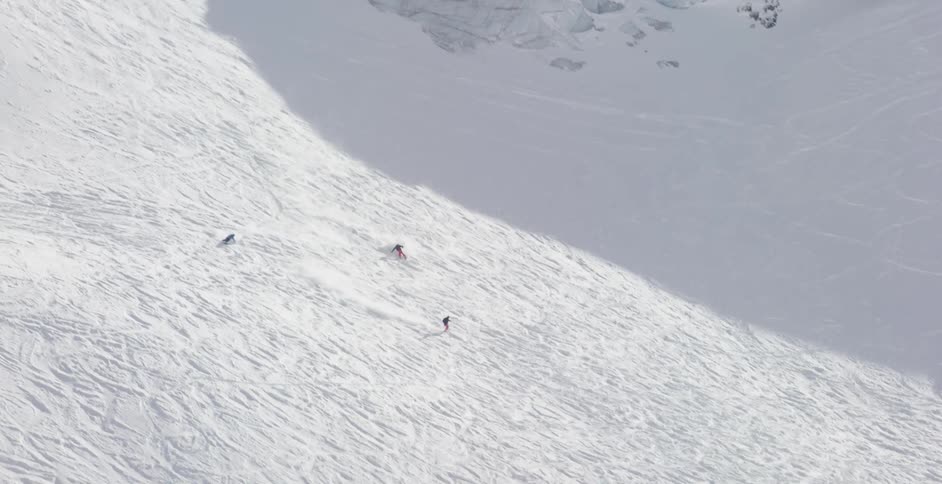 Three skiers ski down a steep slope