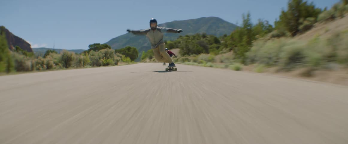 Three people race on skateboards down a street
