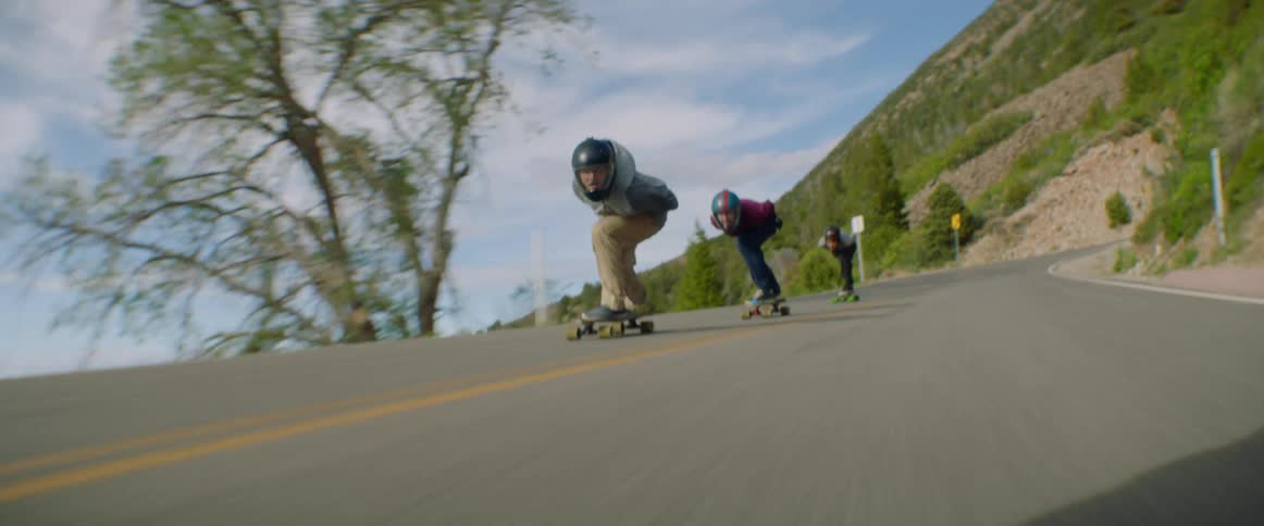 A group of people riding downhill on longboards