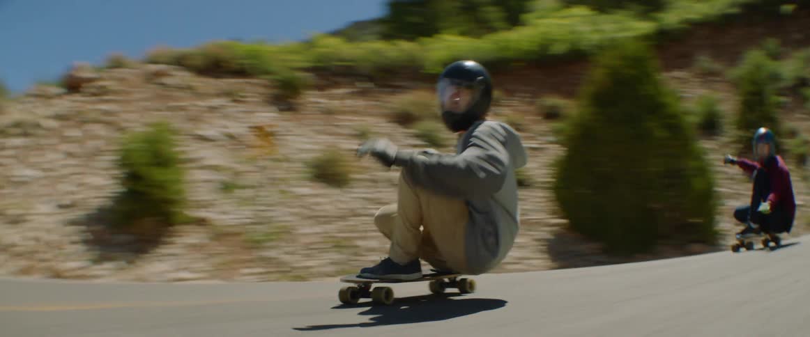 Three teenagers race downhill on skateboards